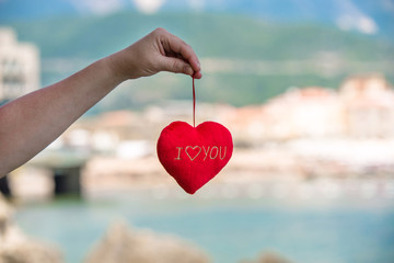 Fototapeta premium Girl holding a symbol of love over the sea 