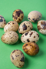 Beautiful spotted fresh quail eggs on a green paper background