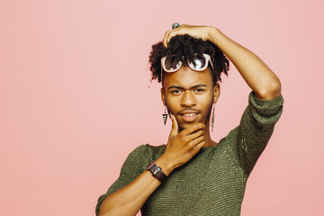 Portrait of a young man holding his head, isolated on pink studio background