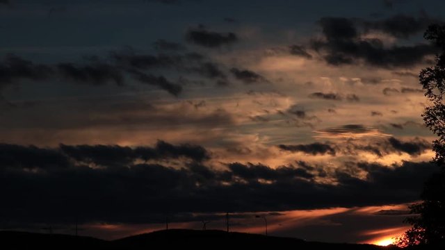 Sunset time-lapse over wind turbines in Sweden with clouds.