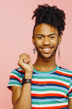Smiling young man with earrings, happy sign on his striped shirt and hand up