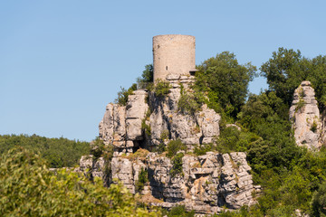 Alter runder Wachturm aus Naturstein auf einem Felsen vor blauem Himmel bei Balazuc