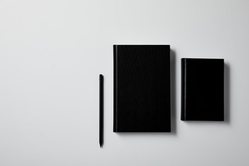 top view of black notebooks with pencil on white surface for mockup
