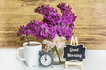 Bouquet of Lilac with Alarm Clock,Cup of Coffee and Good Morning Text on  Wooden Background .Spring...