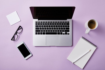 top view of workplace with laptop and smartphone on pink tabletop for mockup