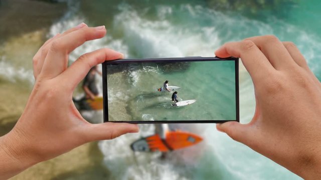 Cinemagraph of Taking Mobile Photo of Unidentified Surfers Entering Sea