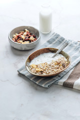 Healthy breakfast. Fresh granola, muesli with yogurt, nuts and dried berries on marble background. 