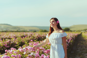 Fototapeta na wymiar Beautiful young woman posing near roses in a garden.