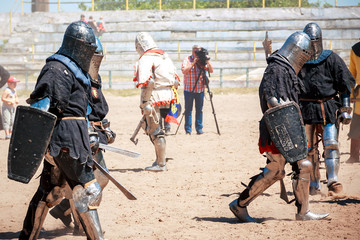 knight battles at the festival of medieval culture. Knights in full armor are fighting with swords