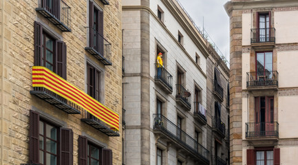 La Senyera ("flag" in Catalan) and mannequin on the balconies in Gothic Quarter of Barcelona. It is the official flag of Autonomous Community of Catalonia and symbol of pride for the Catalan people.