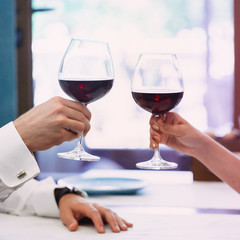 Beautiful young couple with glasses of red wine in luxury restaurant