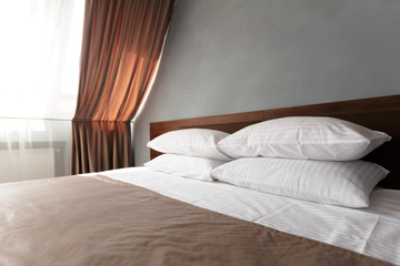 Bed maid-up with clean white pillows and bed sheets in beauty room.