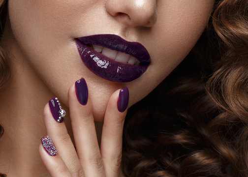 Beautiful girl with evening make-up, purple lips, curls and design manicure nails. beauty face. Photos shot in studio.