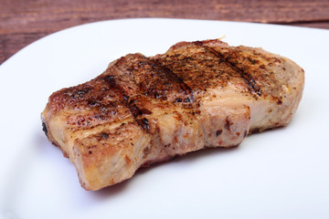 grilled pork chop on plate on wooden board