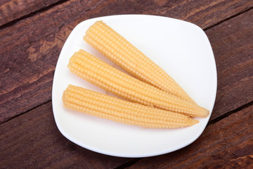 Mini Corn cob preserved on plate on wooden board.