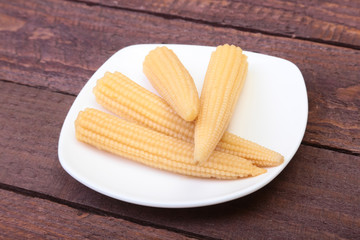 Mini Corn cob preserved on plate on wooden board.