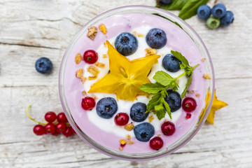A delicious yoghurt dessert with freshly picked berries on a table. 