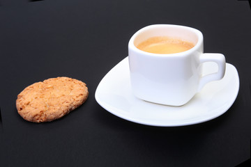 Classic espresso in white cup with homemade cake on black background. Selective focus.