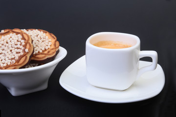 Classic espresso in white cup with homemade cake on black background. Selective focus.
