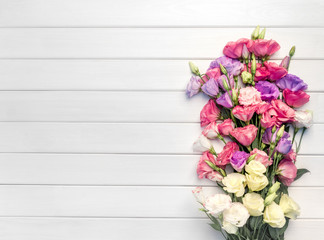 Beautiful bouquet of eustoma flowers on white wooden background. Copy space, top view,