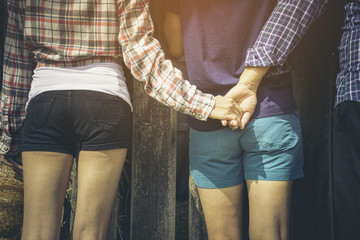 Love triangle, a girl is hugging a guy and he is holding hands with another girl, they are leaning...
