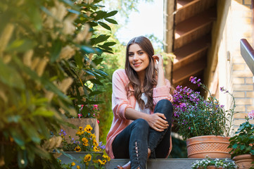 Relaxed young female smiling and looking at camera, sitting on home terrace. Hobby and resting leisure concept.