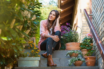 Naklejka premium Relaxed young female smiling and looking at camera, sitting on home terrace. Hobby and resting leisure concept.