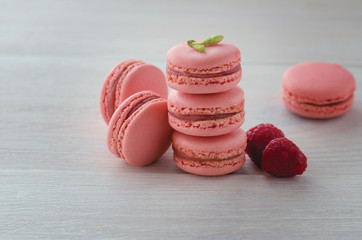 Pink raspberry macarons on wooden table. French dessert macaroons on white  background.