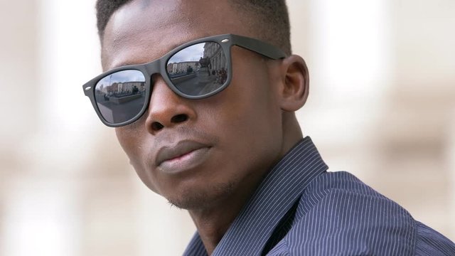 Confident attractive black american man taking off sunglasses, staring at camera