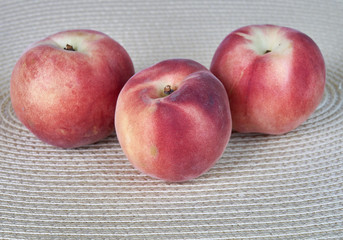 Ripe delicious peach fruit on a light wicker cloth
