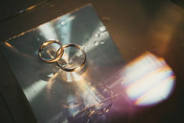Wedding rings on a table with water drops and light reflection