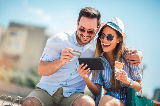 Happy Couple Paying On Line With Credit Card And Digital Tablet On The Street