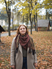 Fototapeta na wymiar Cute young woman in coat walking in autumn Park