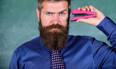 Back to school and studying. Teaching memorization techniques. Teacher bearded man with pink stapler chalkboard background. Pin it on mind. Hipster teacher formal wear with neck tie holds stapler