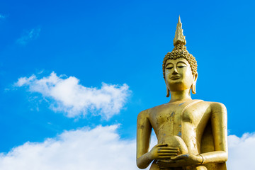 Obraz premium Big golden Buddha statue holding monk's alms bowl with blue sky background.
