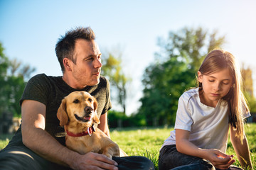 Father and daughter relaxing at park with dog