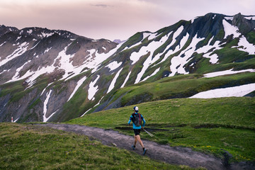 A trail runner running through the mountains at sunset