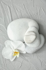 Spa stones and beautiful orchid flower on grey textured background