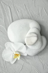 Spa stones and beautiful orchid flower on grey textured background