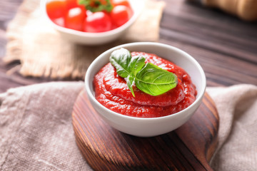 Bowl with tasty tomato sauce on table