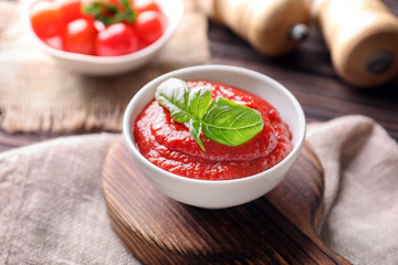 Bowl with tasty tomato sauce on table