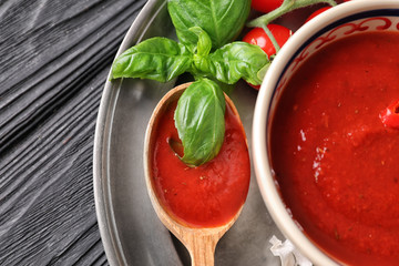 Bowl and spoon with tasty tomato sauce on table, closeup