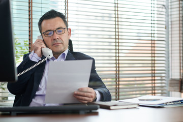 Businessman discussing document on phone