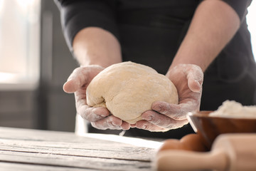 Baker holding dough over kitchen table