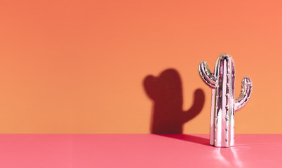 Creative golden cactus on orange background.