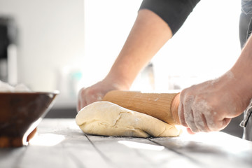 Obraz na płótnie Canvas Baker rolling dough on kitchen table