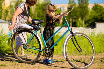 Fototapeta na wymiar Grandmother teaches little granddaughter to ride old big bike