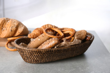 Wicker basket with fresh tasty bakery products on table