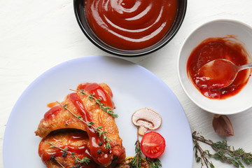 Plate of roasted chicken with barbecue sauce on table, top view
