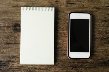 Top view image of blank page notebook with smart phone on the wooden table..